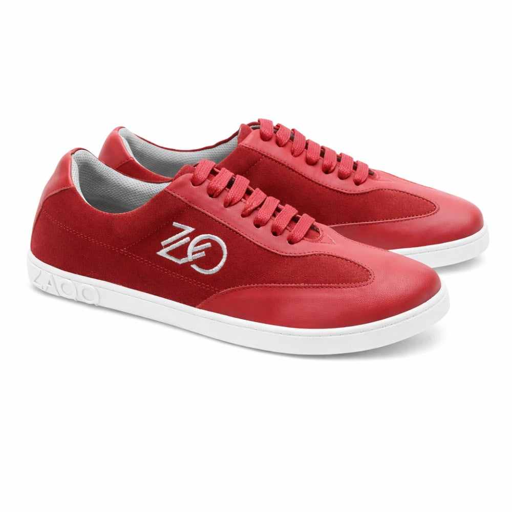 Wir präsentieren den Queensburry Robin von ZAQQ: ein Paar roter Barfuß-Sneaker mit weißer Sohle und Schnürsenkeln, verziert mit einem stylischen Logo an den Seiten. Dieses Design kombiniert kunstvoll rotes Leder und Wildleder für ein elegantes Erscheinungsbild vor einem schlichten weißen Hintergrund.