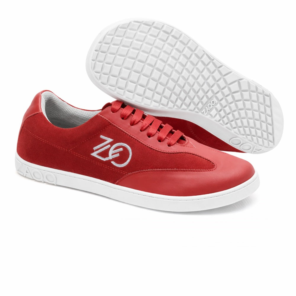 Ein Paar leuchtend rote Queensburry Robin Barfuß-Sneaker von ZAQQ, gefertigt aus rotem Leder. Sie haben weiße Schnürsenkel und Sohlen mit der Nummer 02 auf der Seite. Ein Schuh steht aufrecht, während der andere abgewinkelt ist, um eine gemusterte Sohle und eine breite Zehenbox für zusätzlichen Komfort zu präsentieren.