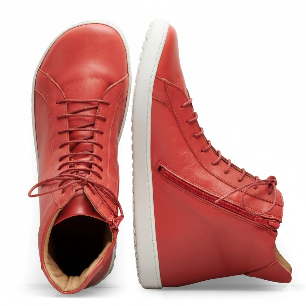 Ein Paar SNAQ Red-Sneaker von ZAQQ, gefertigt aus hochwertigem Nappaleder, mit weißen Sohlen und seitlichen Reißverschlüssen. Ein Schuh steht aufrecht, während der andere auf der Seite liegt, wodurch das detaillierte Innensohlen- und Sohlendesign hervorgehoben wird.